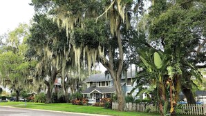 A residential area with houses, a white picket fence, and a road. - Park the car and enjoy Mount Dora! <br>Stay just a 1/2 Mile from Downtown Mount Dora and Lake Dora in our beautifully restored 1950s duplex. <br>Walk to shops & dining! Features fast WiFi, workspace, patio, free parking, and boat parking! (Mount Dora)