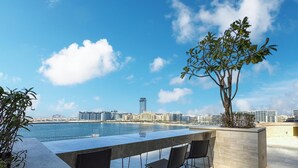 Una terraza en la azotea con piscina, sillas y vistas del horizonte de la ciudad.
