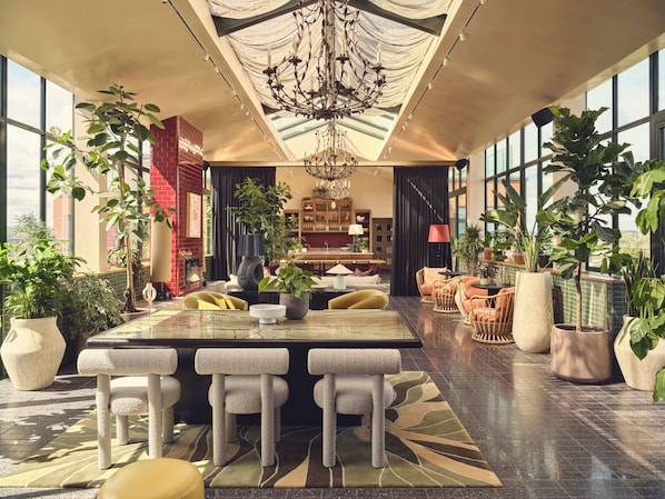 A spacious indoor area with a large central table, multiple seating options, and abundant greenery. - The Upscale Living in London (London)