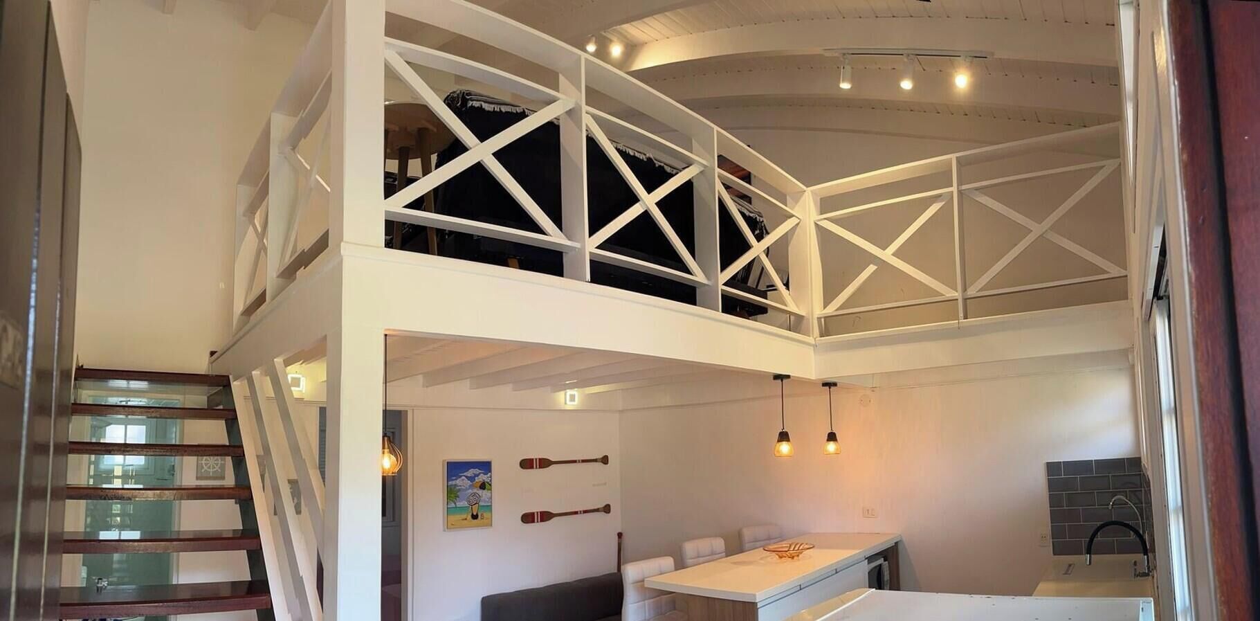 Un interior de varios niveles con zona de comedor, asientos y una escalera.