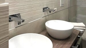 A modern bathroom with two round sinks, a large mirror, and a glass shower enclosure. - Colosseum Luxury Retreat (Roma)