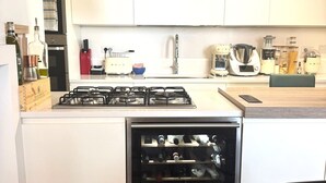 A modern kitchen with white cabinets, a built-in wine cooler, and a gas stove. - Colosseum Luxury Retreat (Roma)