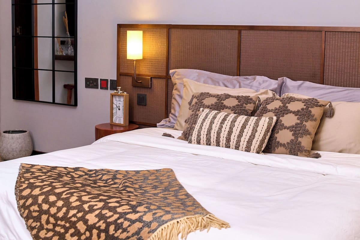Ein Hotelzimmer mit einem großen Bett, einem Nachttisch, einer Wandlampe und abstrakter Kunst.