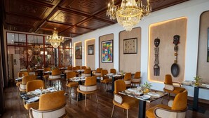 Un restaurante con suelos de madera, sillas anaranjadas, candelabros y obras de arte enmarcadas en las paredes.