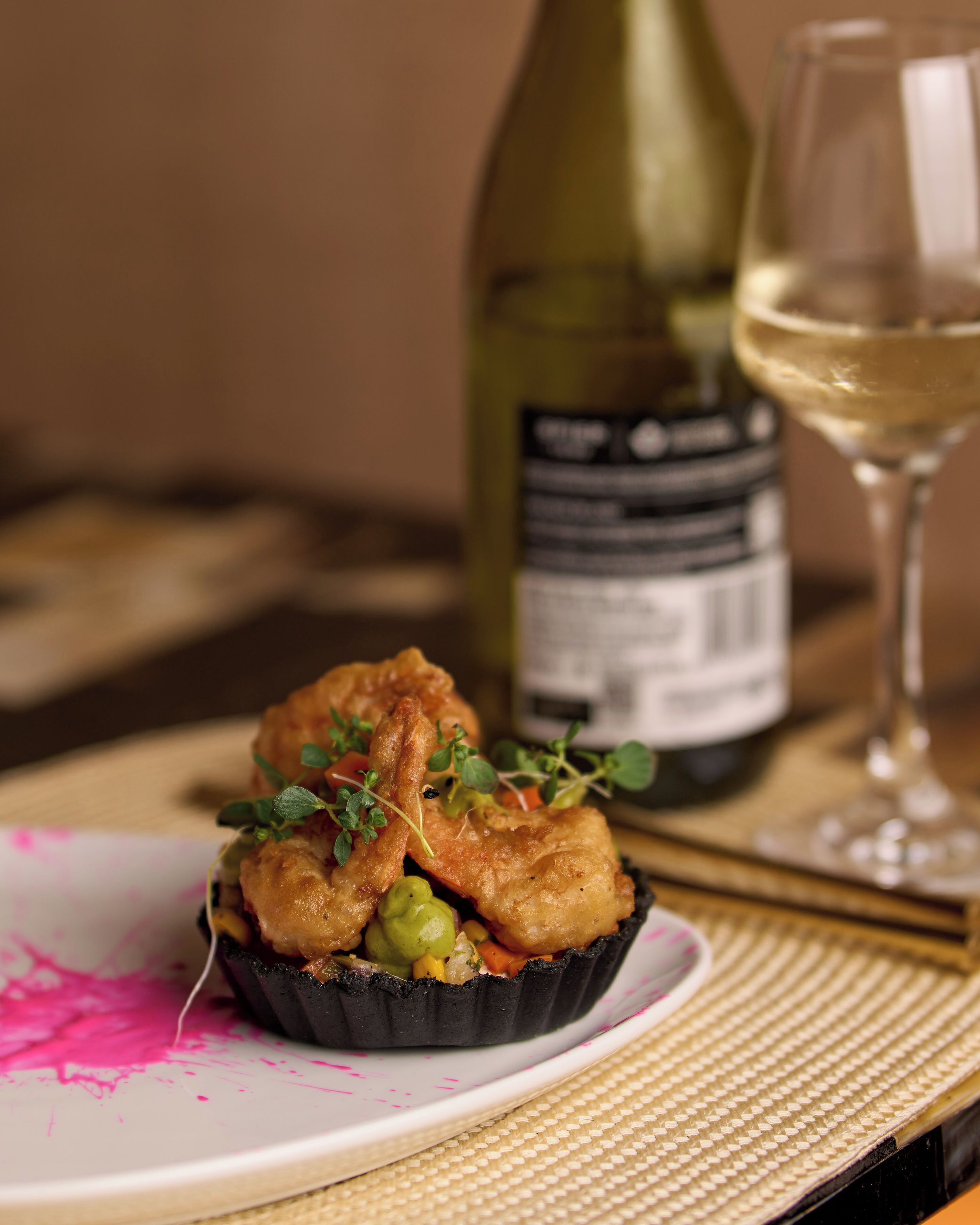 A plate with food, a bottle, and a glass on a table.