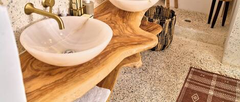 A bathroom with two sinks, a wooden vanity, a bathtub, and a towel rack.