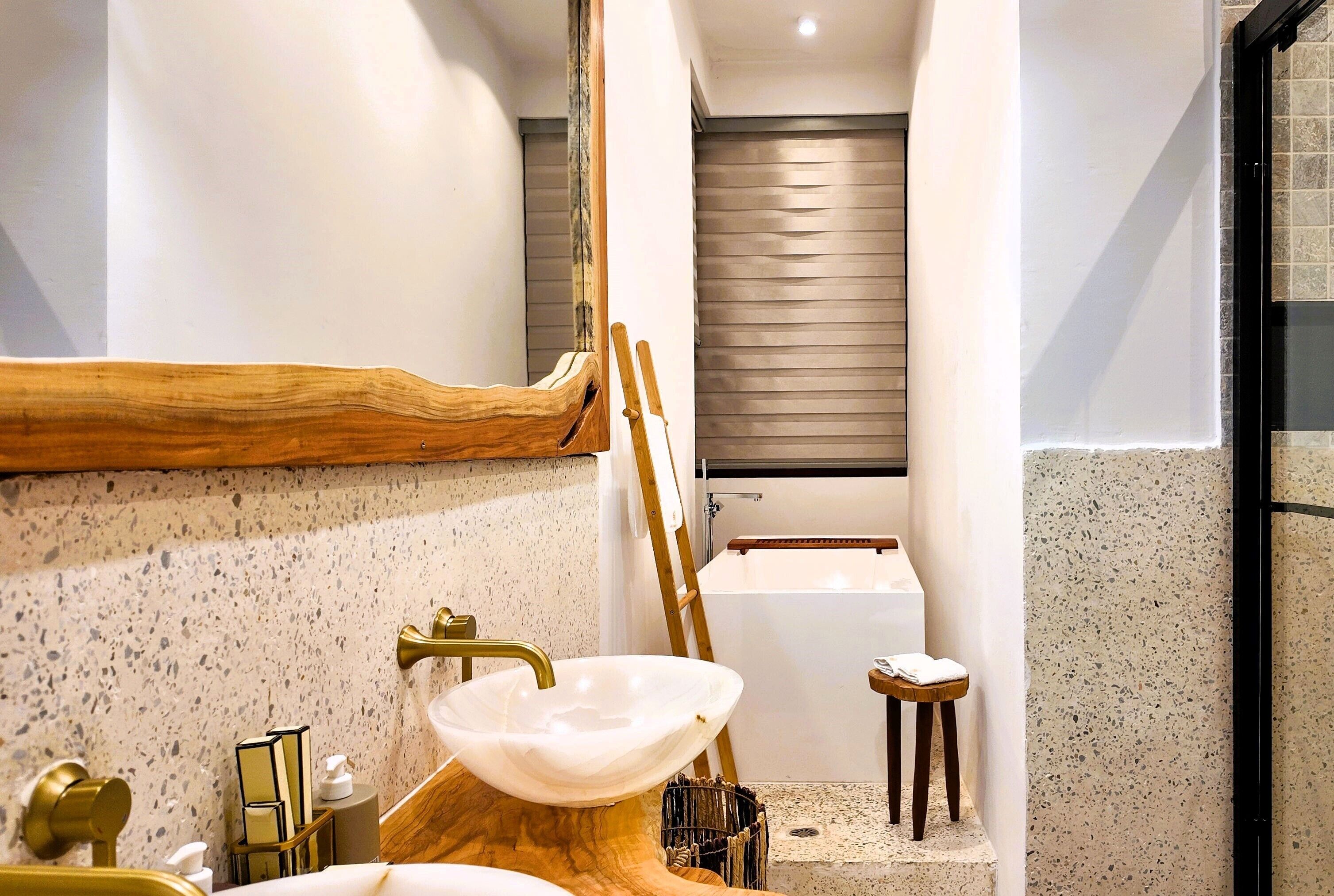 Un baño con un tocador de madera independiente, un lavamanos blanco tipo lavabo y una bañera.