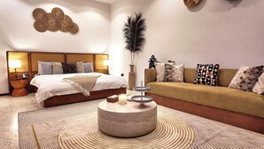 Una habitación de hotel con una cama, un sofá, una mesa de centro redonda y un adorno en la pared.