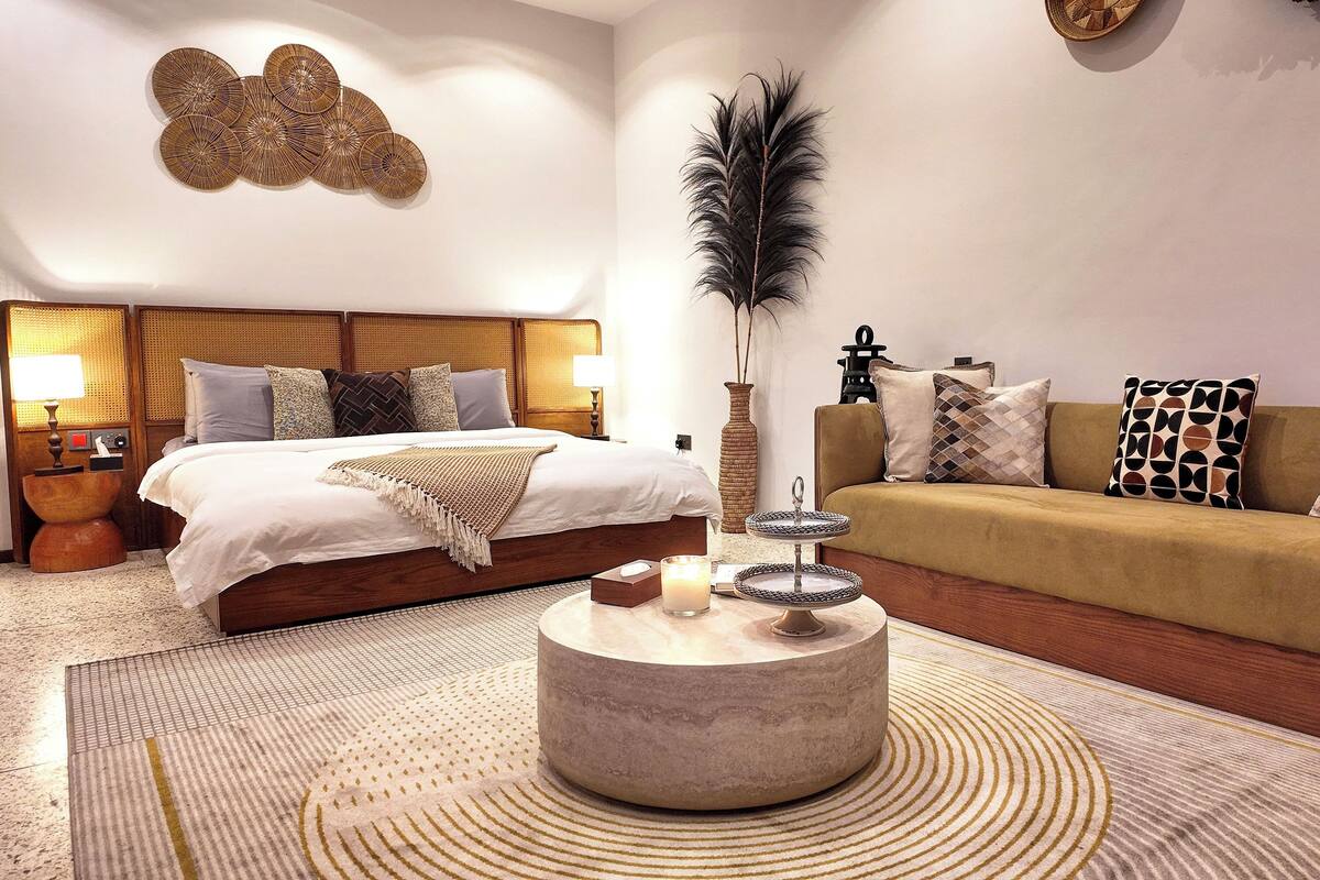 Ein Hotelzimmer mit Bett, einer Couch, einem runden Couchtisch und einem dekorativen Wandbild.