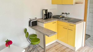 Una cocina compacta con tostadora, cafetera y lavamanos.