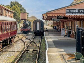 A train station with a platform, a vintage train, and a shop named 'The Buffer Store.'