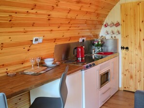 Una cocina compacta con paredes de madera, estufa, pileta y horno pequeño.