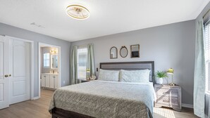 A bedroom with a large bed, a nightstand, a dresser, a mirror, and a ceiling light. - Family & Pet Friendly, New Plunge Pool & Grill, No Stairs,Walk 2 Beach,Sleeps 12 (Destin)