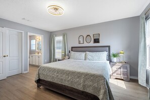 A bedroom with a large bed, a nightstand, a dresser, a mirror, and a ceiling light. - Family & Pet Friendly, New Plunge Pool & Grill, No Stairs,Walk 2 Beach,Sleeps 12 (Destin)