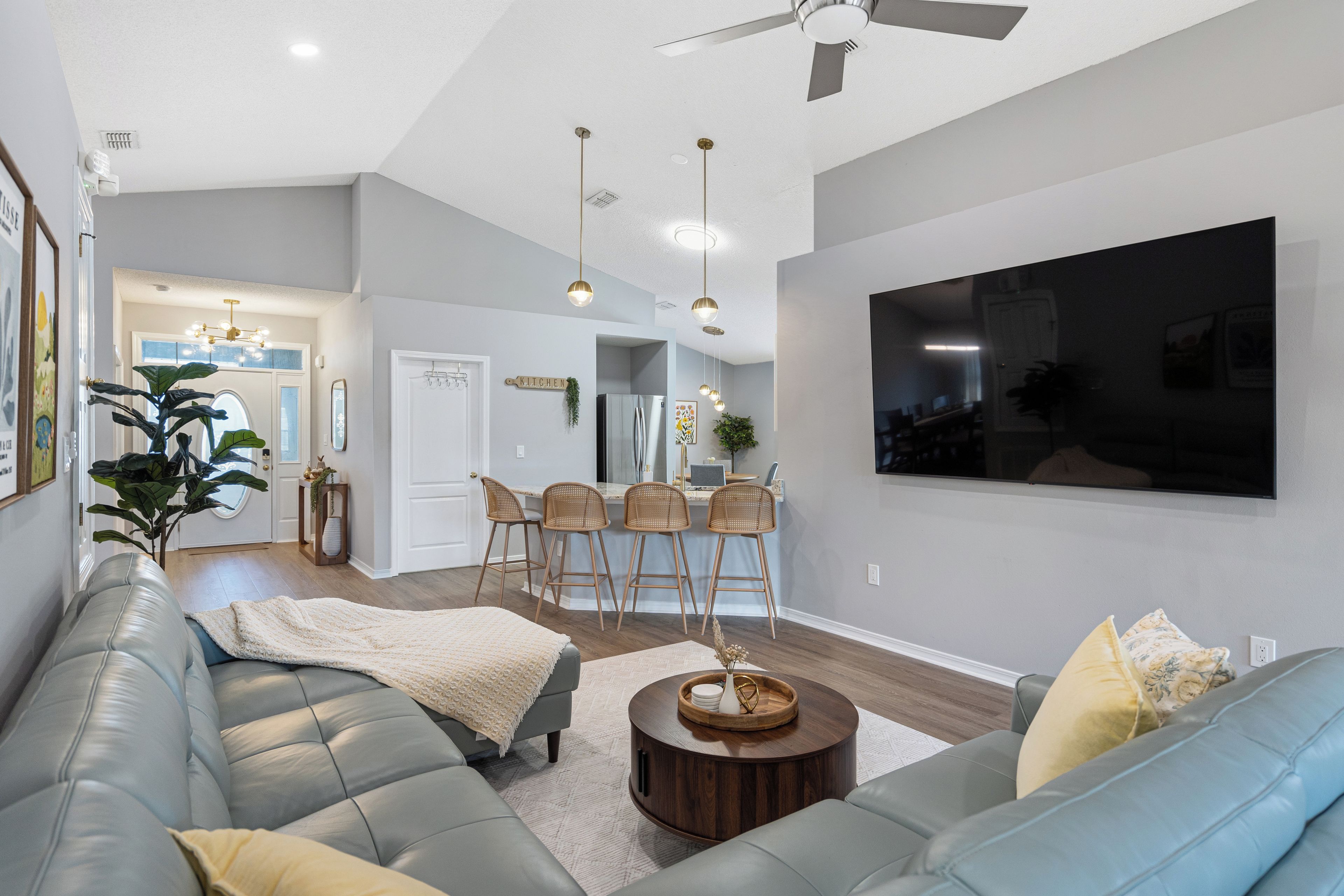 A modern living room with a sectional sofa, a round coffee table, and a dining area with a kitchen in the background.