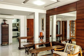 A modern living room with a glass coffee table, wooden furniture, and a large mirror reflecting the space. -  Leme 3 Quartos Conforto 2 min Praia (Rio de Janeiro)