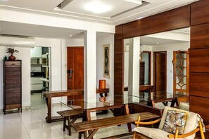Uma sala de jantar moderna com mesa de vidro, cadeiras de madeira e um espelho grande.