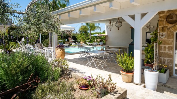 Un espace extérieur abrité comprenant une piscine, des chaises longues et des plantes en pot.