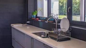 A modern kitchen with a large window, dark tiles, and a dish rack.