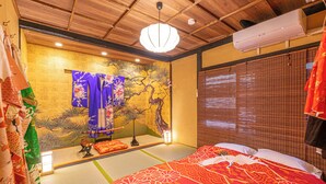 Ein traditioneller japanischer Raum mit Tatami-Boden, Futonbett, Shoji-Schirm und einer hängenden Shoji-Tür.