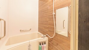 Ein Badezimmer mit Holzvertäfelung, einer weißen Badewanne und einer Dusche mit Handbrause.