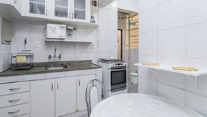 Une cuisine moderne avec des armoires blanches, un four encastré, un évier et un plan de travail muni d’un égouttoir à vaisselle.