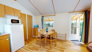 A compact kitchen with a microwave, refrigerator, and wooden cabinets. - Le Bois Perdu (Saint-Jean-de-Monts)