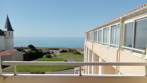 Balcó amb taula per a dues persones, amb vista al mar, una església i una platja.