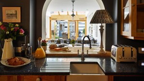 Una cocina con pileta, tostadora y vista al comedor por un arco.