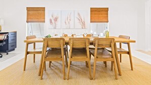 Un comedor con una mesa y sillas de madera, una silla de oficina negra y una lámpara.