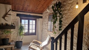 Un intérieur rustique avec un plafond en bois, un fauteuil à bascule, une plante en pot et un luminaire suspendu.