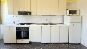 Ett kök med vita skåp, en spis, en mikrovågsugn och en diskmaskin.
