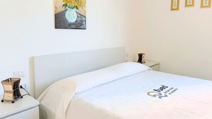 Ett hotellrum med en säng, ett nattduksbord, en lampa, en tavla med solrosor och tre inramade bilder på väggen.