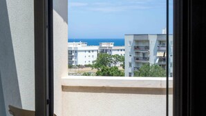 Ein Balkon mit Stuhl und Tisch, mit Blick auf ein Gebäude und einen klaren Himmel.