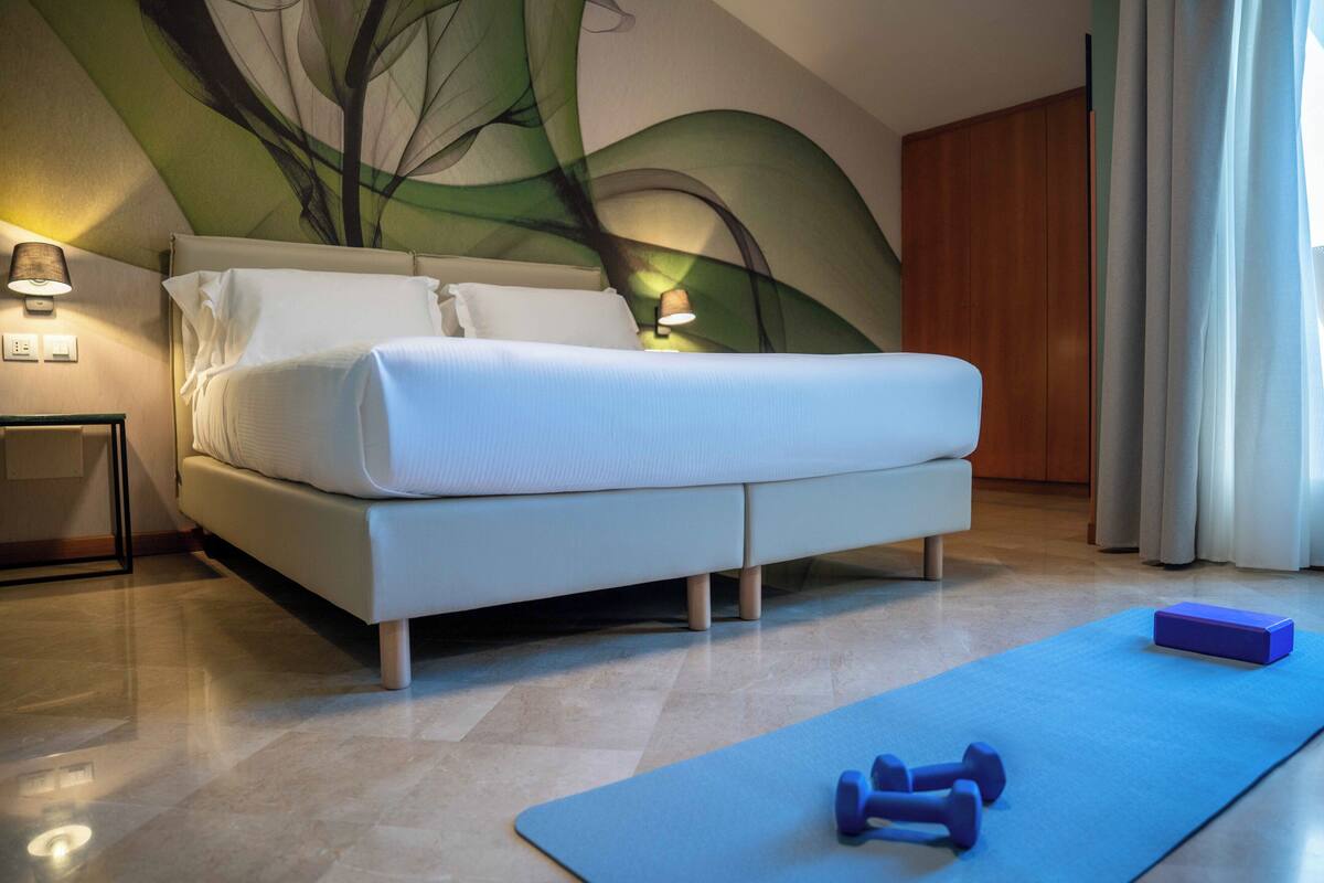 Un dormitorio con una cama, una colchoneta azul y mancuernas.