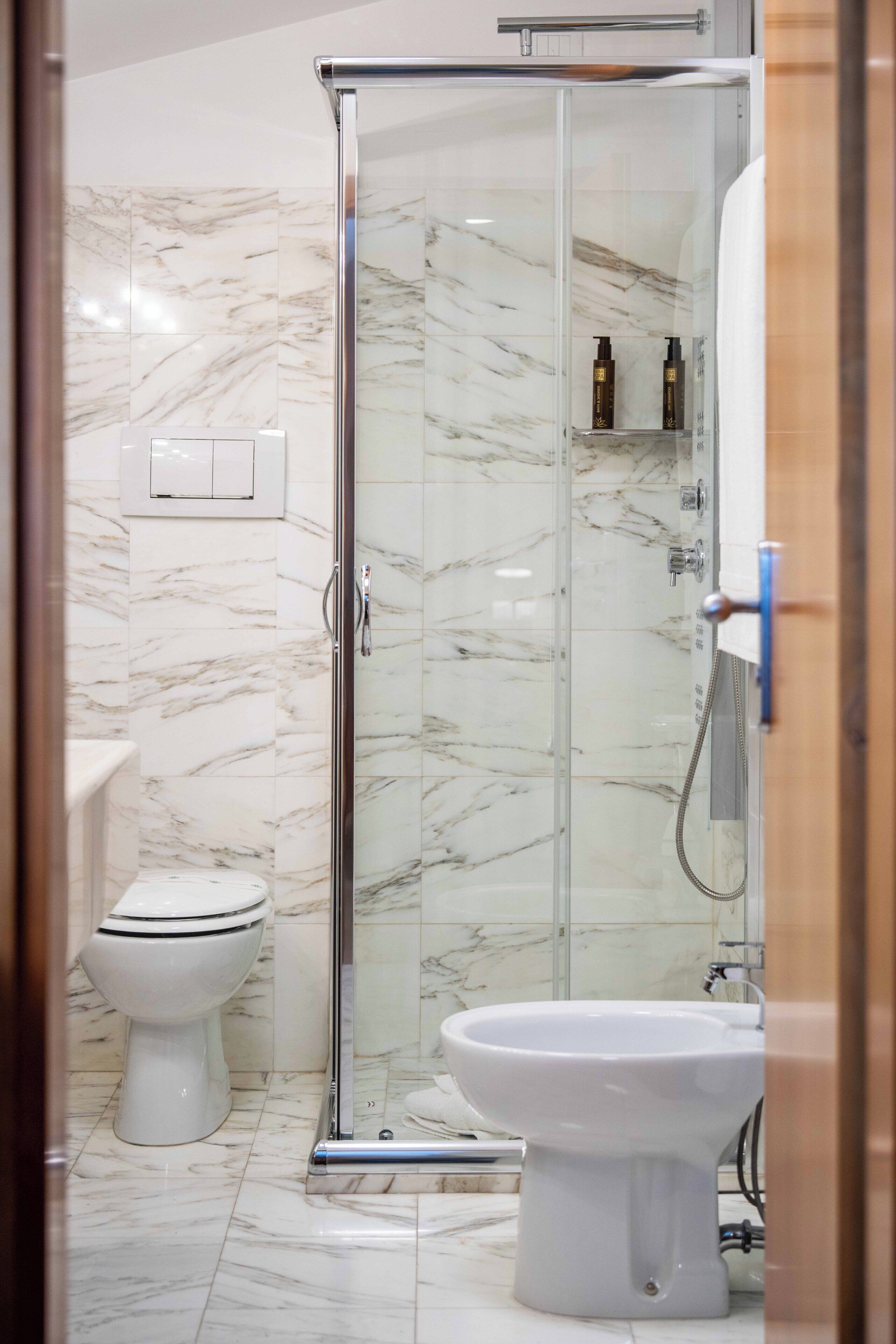 A bathroom with a glass-enclosed shower, a toilet, and a bidet.