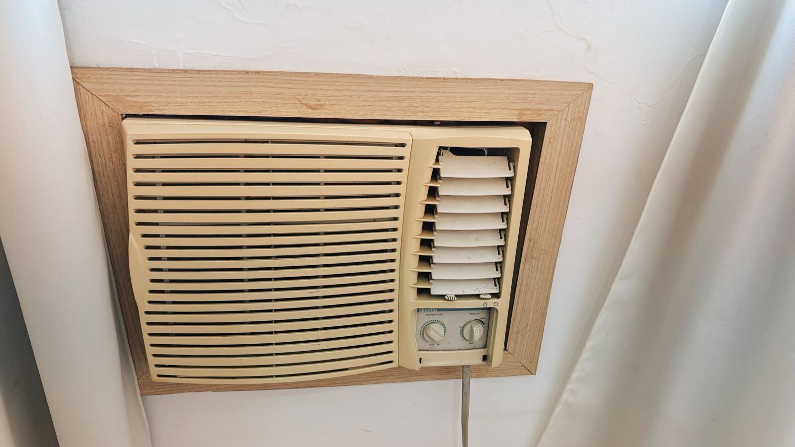 Un climatiseur mural de style rétro, doté d’un cadre en bois et de deux boutons de commande.