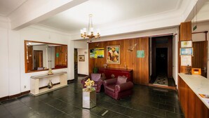 En lobby med reception, spejl, lysekrone, lædersofaer og et konsolbord.