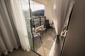 A balcony with a glass door, two chairs, and a table.