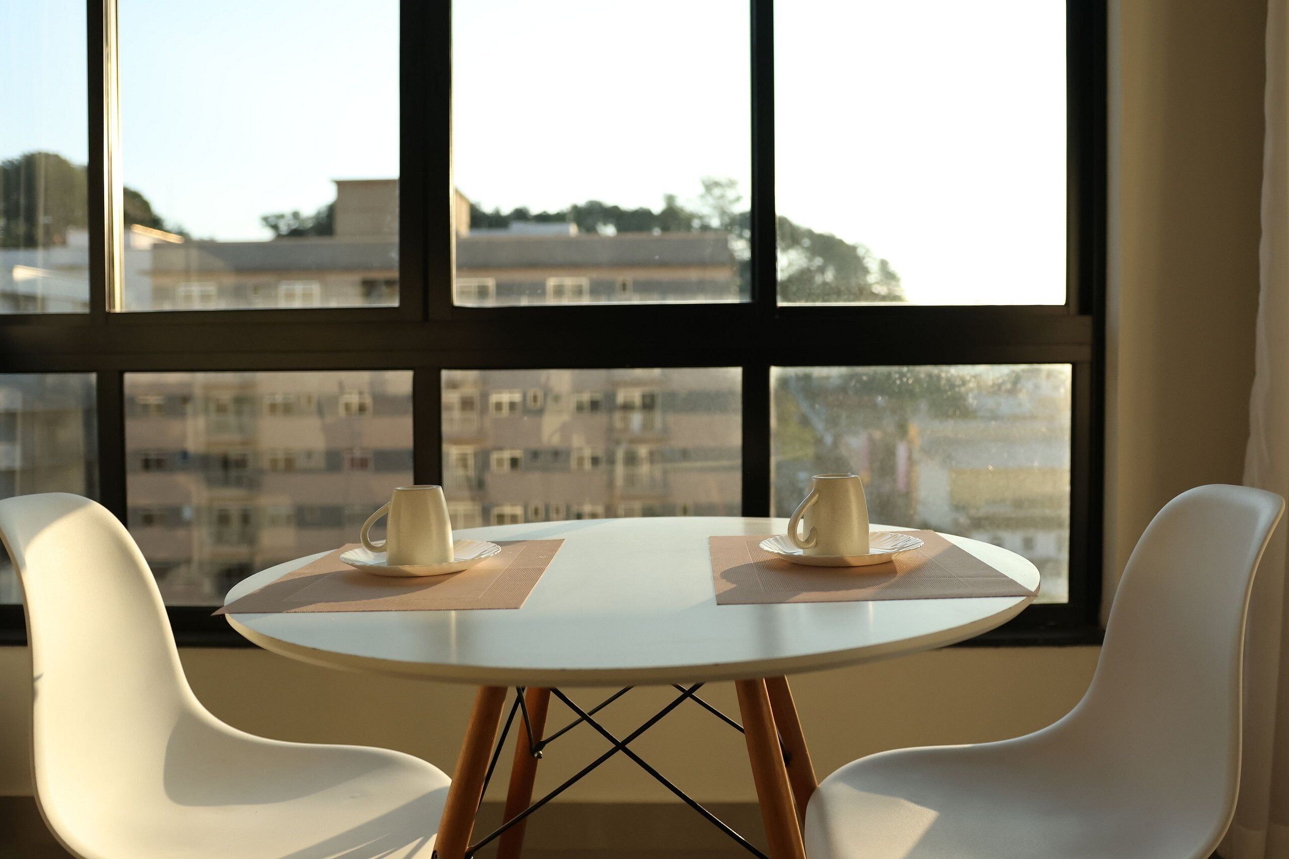 A room with a round table, two chairs, and a view through large windows.