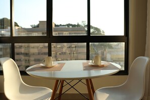 A room with a round table, two chairs, and a view through large windows.
