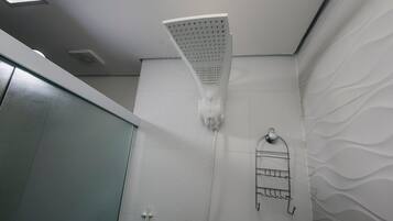 A showerhead with water flow, a towel rack, and a textured wall.