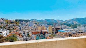 A cityscape with a variety of building types, including residential and commercial structures, set against a backdrop of hills and clear skies. - Prime Center View - Beautiful view. Do it all on foot! (São Lourenço)