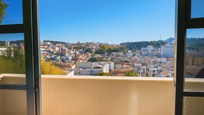 A view from a window with tiled walls, overlooking a cityscape with buildings and hills. - Prime Center View - Beautiful view. Do it all on foot! (São Lourenço)