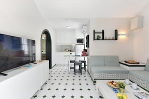 A modern living space with a TV, sofa, dining area, and kitchen. - Campo Golf 26 by VillaGranCanaria (Las Palmas de Gran Canaria)
