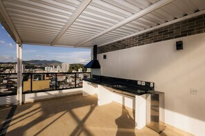 Un balcon donnant sur un paysage urbain, un barbecue noir et un mur blanc.