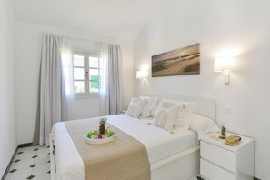 A neatly arranged hotel room with a bed, bedside table, and a painting on the wall. - Campo Golf 27 by VillaGranCanaria (Las Palmas de Gran Canaria)