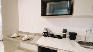 Eine moderne Küche mit Mikrowelle, Kaffeemaschine und Kochgeschirr auf der Arbeitsfläche.