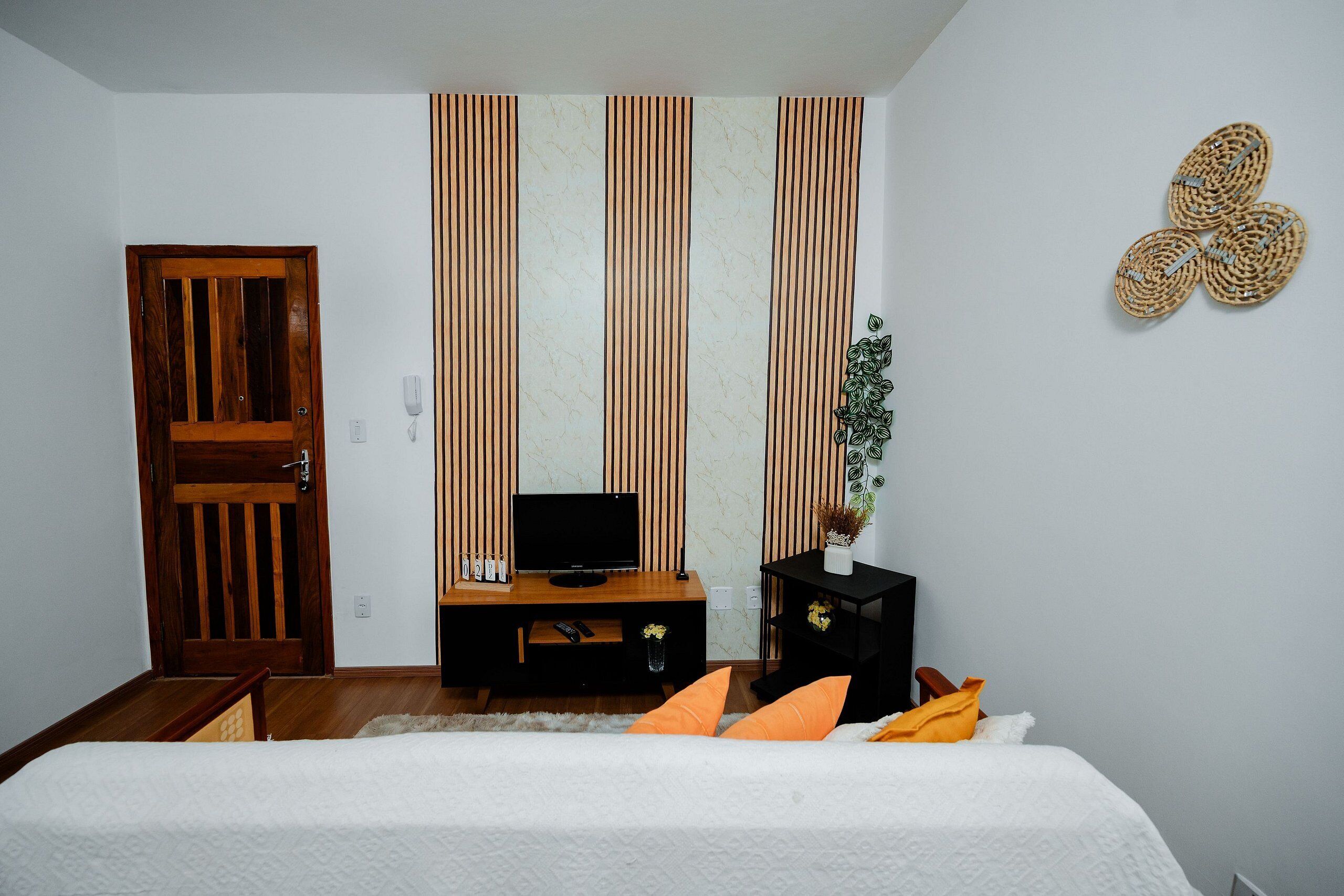 A bedroom with a bed, a TV, a desk, and a door.