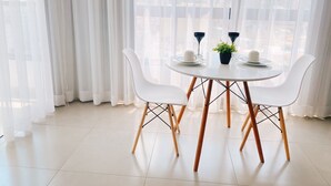 Un comedor moderno con una mesa redonda, sillas blancas y vistas a través de cortinas traslúcidas.